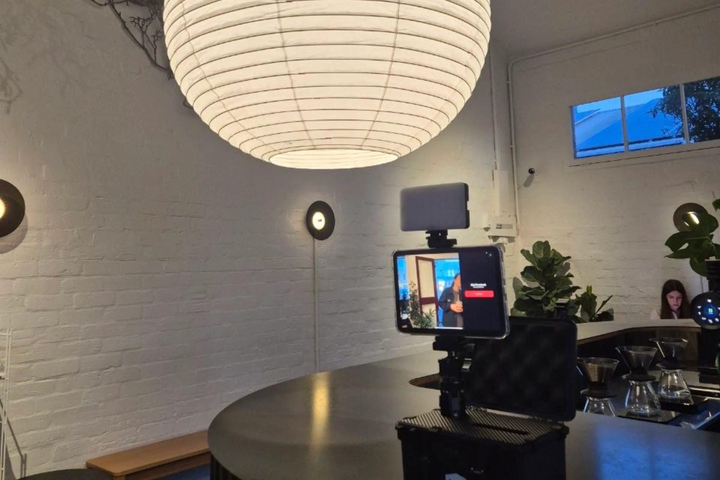 The booth set up on a café table under a paper lantern, its screen showing the live camera.