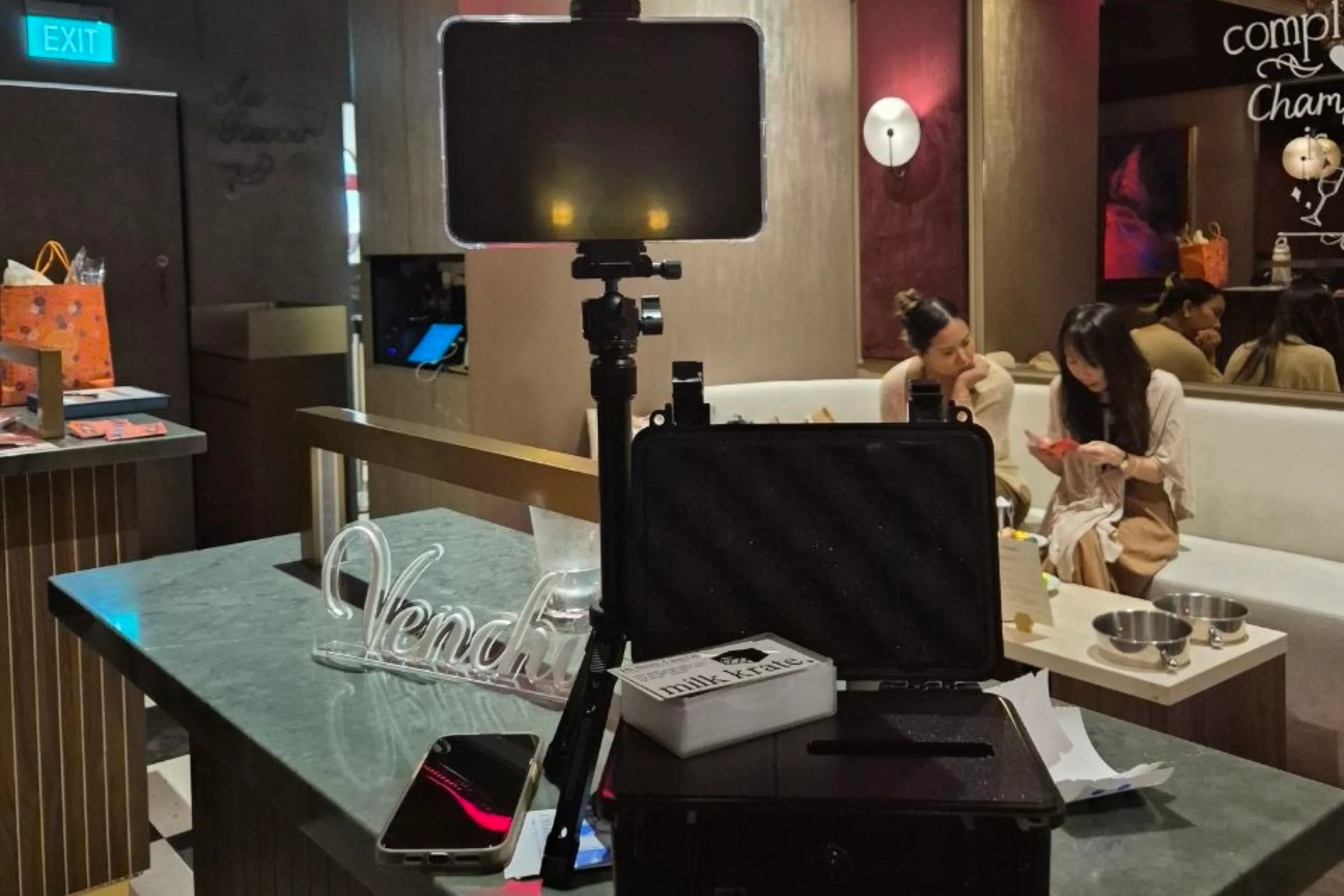 The booth packed into its hard case on a lounge table, guests seated behind it.