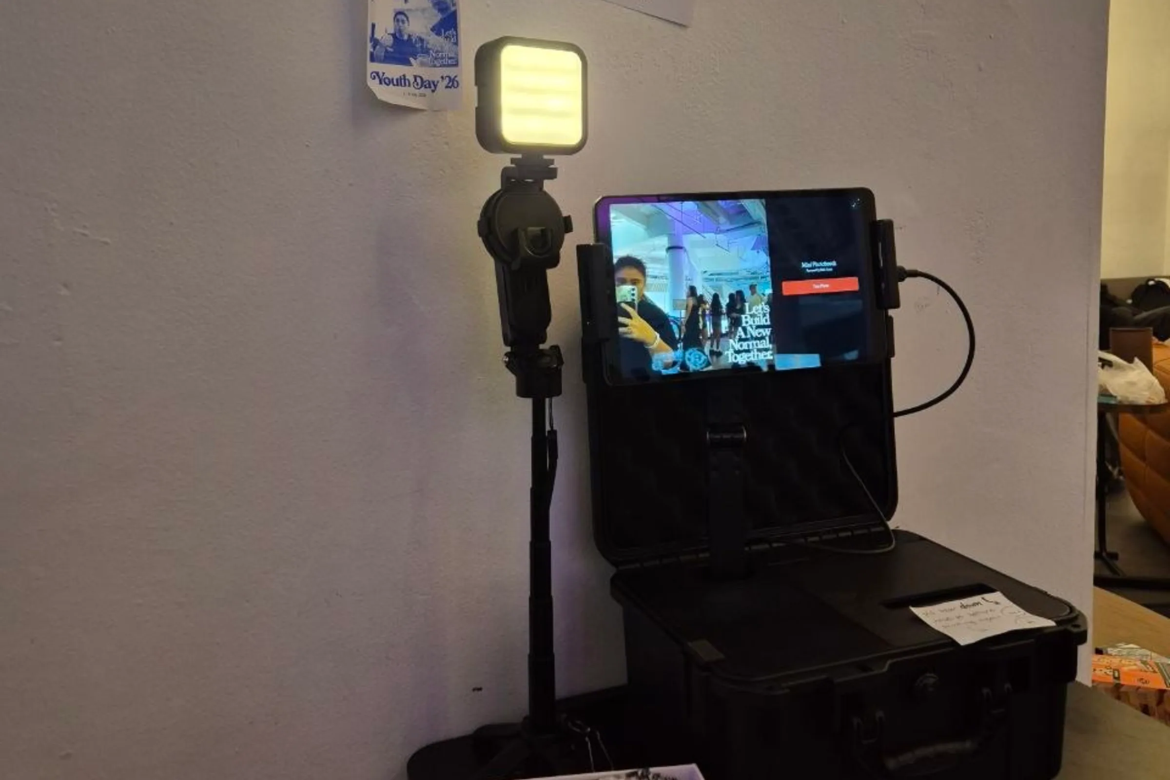 The booth at Youth Day '26: a light on a stand beside the open case and its screen.